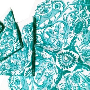May include: A set of teal blue napkins with a repeating pattern of cherubs, flowers, and vines on a white background.