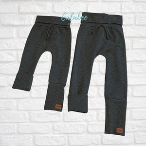 May include: Two pairs of charcoal gray sweatpants with a drawstring waistband and cuffed legs. The sweatpants are made of a soft, comfortable fabric.