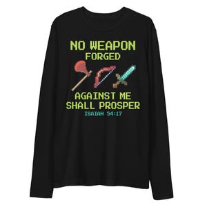 Pode incluir: Camiseta preta de manga comprida com um design pixelizado de um machado, arco e espada vermelhos. O texto verde diz "NO WEAPON FORGED AGAINST ME SHALL PROSPER" e "ISAIAH 54:17".