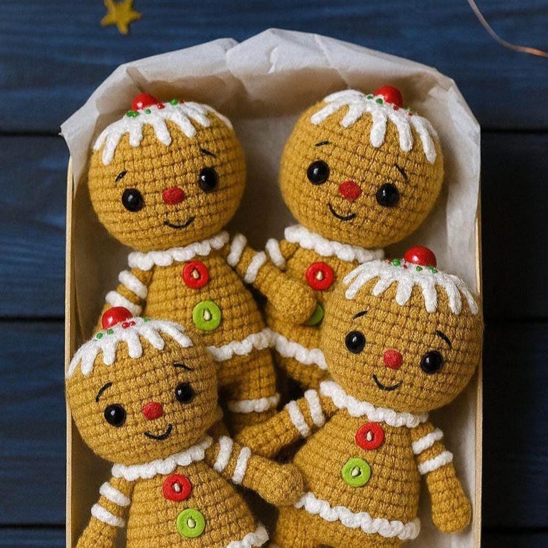 May include: Four handmade crochet gingerbread men dolls in a box. Each doll has a yellow body, white icing details, and a red cherry on top. They have black eyes, red noses, and green and red buttons.