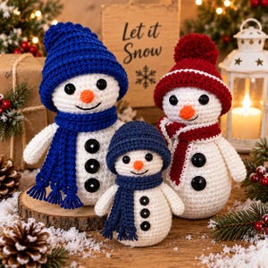 May include: Three crocheted snowmen figures with white bodies, black button eyes and torso buttons, and orange noses. One wears a blue hat and scarf, one a red hat and scarf, and the smallest wears a dark blue hat and scarf. They are arranged together.