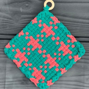 May include: A green and coral woven pot holder with a wooden loop handle.