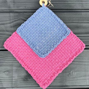 May include: Two crocheted pot holders, one pink and one blue, with a wooden ring attached to the blue pot holder.