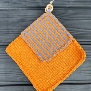 May include: A set of two crocheted pot holders. The top pot holder is a striped design in grey and orange. The bottom pot holder is a solid orange colour. Both pot holders have a crocheted border.
