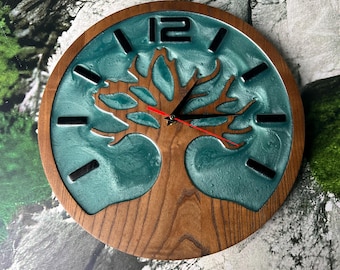 May include: A round wooden wall clock with a teal resin background and a tree of life design. The clock has black numerals and hands, with a red second hand. The clock is approximately 12 inches in diameter.