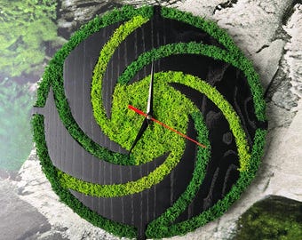 May include: Round wall clock with a black wooden face and a spiral design of green moss. The clock hands are black with a red second hand. The clock's design is a unique, naturalistic decor piece.
