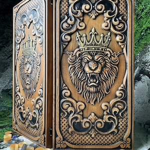 Puede incluir: Un juego de backgammon de madera con un león tallado con una corona. El juego es marrón con detalles oscuros e incluye fichas y dados. La talla del león es detallada y el juego tiene un diseño ornamentado.