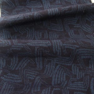 May include: A long, rectangular fabric runner featuring a dark navy blue base color with a repeating geometric pattern composed of thin, light blue stitched lines that form interconnected angular shapes across the entire surface of the textile.