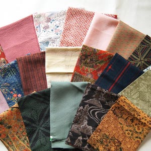 May include: A collection of rectangular fabric swatches arranged in a fan shape, featuring a variety of colors including red, pink, blue, green, brown, and black, with diverse patterns such as floral, geometric, striped, and solid textures.