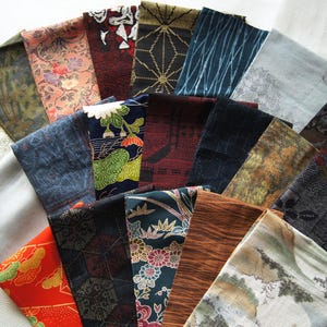 May include: A collection of rectangular fabric swatches arranged in a fan shape, featuring a variety of patterns including floral, geometric, wood grain, and landscape designs in colors such as red, blue, brown, black, and grey.