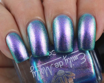 May include: A bottle of blue nail polish with a holographic finish. The bottle is labeled "Moon Wrap" and has a flower logo.