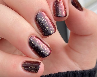 Here Nor There - A black to red multichrome nail polish with metallic gold flakes.
