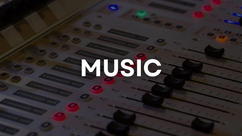 May include: Close-up of a sound mixing console with the word "MUSIC" in white capital letters. The console has numerous sliders, buttons, and lights, with a dark background. The image suggests a recording studio or live performance setting.