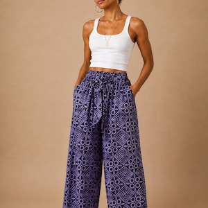 Puede incluir: Una camiseta de tirantes blanca de canalé combinada con pantalones anchos con un estampado geométrico en morado oscuro y claro. Los pantalones tienen cintura elástica con un cinturón de tela a juego y dos bolsillos laterales de corte holgado.