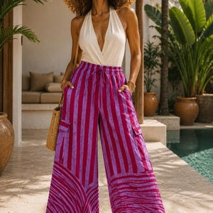 May include: A white halter-neck bodysuit paired with wide-leg cargo trousers featuring a magenta and purple striped pattern with a textured graphic design at the hem, an elastic drawstring waist, and side cargo pockets with flaps.
