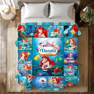 May include: A colorful blanket featuring a collage of images of a mermaid with red hair and a purple seashell top. The blanket has a blue background with the name "Dannii" in a decorative font.