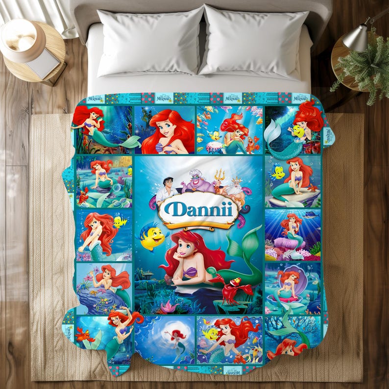 May include: A colorful blanket featuring a collage of images of a mermaid with red hair and a purple seashell top. The blanket has a blue background with the name "Dannii" in a decorative font.