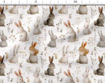 May include: Fabric with a repeating pattern of watercolor-style bunnies in various poses. The bunnies are in shades of gray, brown, and tan, with pink or orange ears. The background is white with small floral and plant accents.