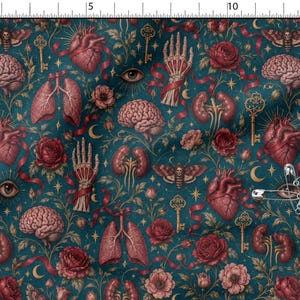May include: A dark teal fabric featuring a repeating pattern of anatomical hearts, brains, lungs, kidneys, skeletal hands, moths, roses, and gold keys. A silver safety pin is attached to the fabric, which is placed next to a 15-inch ruler.