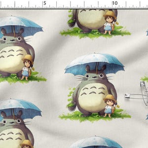 Può includere: Tessuto con un motivo ripetuto del personaggio Totoro del film d'animazione Il mio vicino Totoro. Ogni Totoro è sotto un ombrello blu con una bambina. Lo sfondo è di colore crema chiaro.