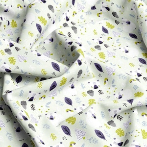 May include: A light green fabric with a repeating pattern of leaves, acorns, and small trees in shades of purple, green, and gray. The fabric is folded, showing the detailed design and texture. The overall theme is nature.