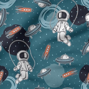Könnte beinhalten: Ein tealfarbenes Stoffmuster mit Cartoon-Illustrationen von Astronauten, Raumschiffen und UFOs. Die Astronauten springen Seil. Die Raketen sind orange und die UFOs sind grau. Der Hintergrund hat dunkelblaue Kreise und weiße Punkte.