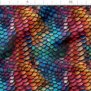 May include: A colourful fabric with a watercolour design of overlapping scales in shades of blue, teal, orange, yellow, and red. The pattern creates a textured, iridescent effect, reminiscent of mermaid scales.