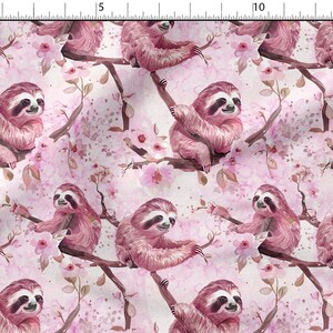 May include: A repeating pattern of sloths and pink cherry blossoms on a white background. The sloths are a dusty rose color and are perched on brown branches. The flowers are a soft pink with a watercolor effect.