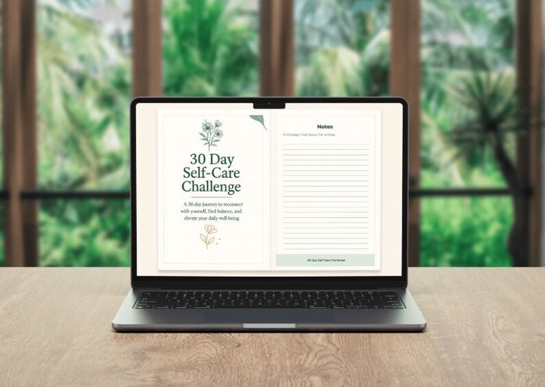 May include: A laptop displaying a digital self-care journal. The screen shows the title "30 Day Self-Care Challenge" with floral illustrations. The journal includes space for notes and prompts for daily well-being, set against a blurred green background.