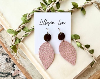 May include: A pair of pink leather earrings with a brown circle accent. The earrings are on a white card with the text "Lillylan Lou" written on it.