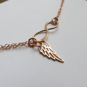 Pu&ograve; includere: Una collana in oro rosa con un ciondolo a forma di infinito e un delicato ciondolo ad ala d'angelo.