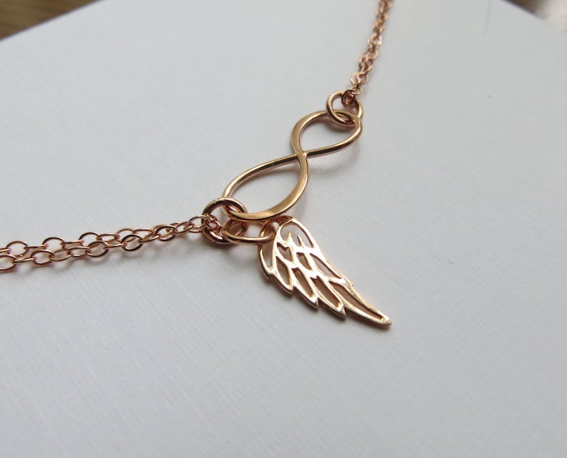 Pu&ograve; includere: Una collana in oro rosa con un ciondolo a forma di infinito e un delicato ciondolo ad ala d'angelo.