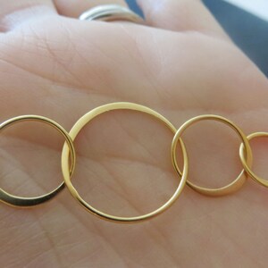 May include: A gold necklace with five interlocking circles of varying sizes.
