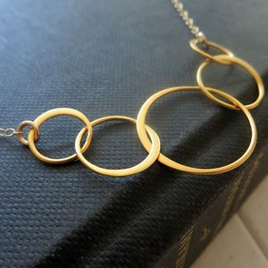 May include: A gold necklace with five interlocking circles of varying sizes.