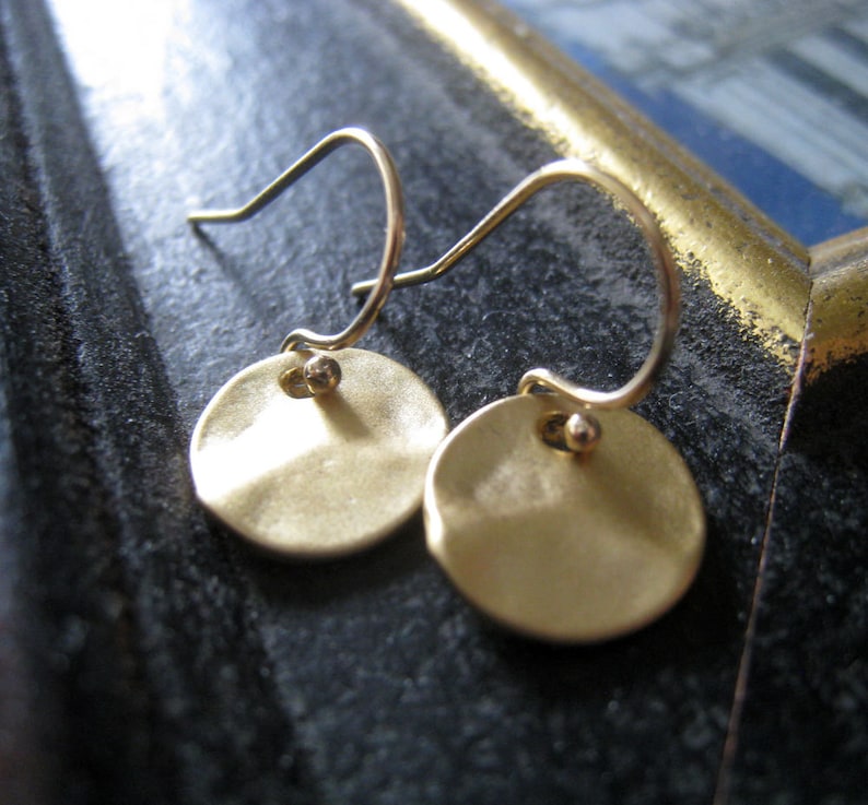 a pair of gold-toned earrings with a simple, round disc design.