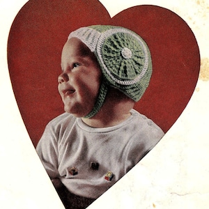 May include: A baby wearing a green and white crocheted hat with a heart-shaped frame around them.