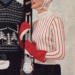 May include: A woman wearing a white and red striped sweater with a white knit hat. She is holding a pair of skis and wearing red ski gloves.