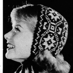 以下が含まれることがあります： 白黒のベビーキャップの画像。キャップは青と白の幾何学模様です。キャップは黒い紐で結ばれています。画像上部のテキストは「BLUE-AND-WHITE NORWEGIAN BABY CAP」と書かれています。