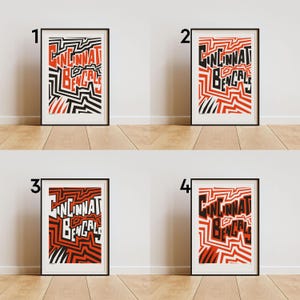 May include: Four framed art prints with the text "Cincinnati Bengals" in a bold, geometric design. The prints feature a red, black, and white color scheme. The artwork is displayed against a white wall and a wooden floor.