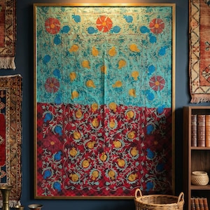 Op de afbeelding: Een grote rechthoekige wandhanger in een gouden lijst, met een verdeeld ontwerp met een turquoise bovenhelft en een donkerrode onderhelft. De stof is geborduurd met herhalende bloemmotieven en gouden granaatappelmotieven over het geheel.