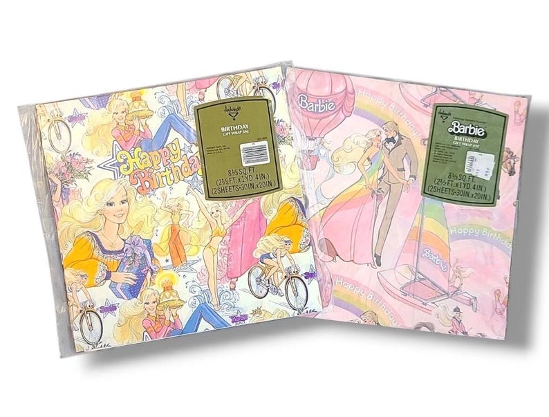 May include: Two sheets of Barbie birthday gift wrap in a plastic sleeve. The wrap features illustrations of Barbie in various outfits, along with the text "Happy Birthday." The background colors are pink and white.