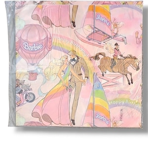 May include: A package of Barbie-themed paper napkins. The napkins feature illustrations of Barbie and Ken, sailboats, a hot air balloon, and a horse. The words "Happy Birthday!" and the Barbie logo are also visible.