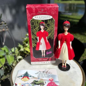 May include: A 1998 Hallmark Keepsake Ornament titled Silken Flame featuring a Barbie doll wearing a red velvet coat, white skirt, red hat, and pearl necklace. The set includes the original red collector box and a promotional club insert.