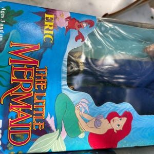May include: A vintage "The Little Mermaid" toy box featuring Ariel, Eric, and Sebastian. The box is blue with colorful graphics and the Tyco logo. The toy is for ages 3 and up.