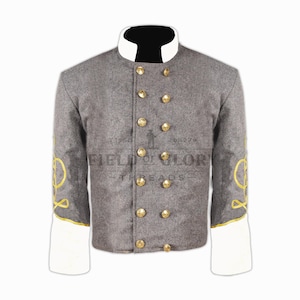 Op de afbeelding: Een grijze wollen jas met gouden knopen en afwerking. De jas heeft een witte kraag en manchetten en gouden borduursels op de mouwen. De tekst "FIELD OF GLORY THREADS" is op de jas gedrukt. Historisch kledingstuk.