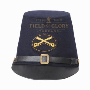 May include: A dark blue Civil War kepi hat with a black leather brim and strap. The hat features a gold emblem with crossed sabers and the text "FIELD OF GLORY - THREADS".