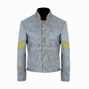 Peut inclure: Une veste en laine grise avec des bordures et des boutons dorés. La veste a un col officier et des rayures jaunes sur les manches. Le texte "FIELD & GLORY THREADS" est visible sur la veste.