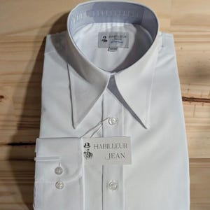 Puede incluir: Camisa blanca de vestir con cuello puntiagudo y pu&ntilde;os con botones. La camisa tiene una etiqueta que dice "Habilleur Jean".
