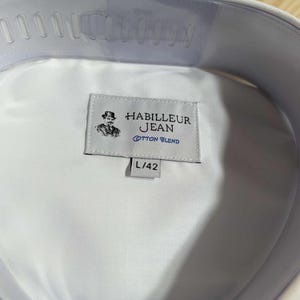 Puede incluir: Camisa blanca de cuello con una etiqueta que dice "Habilleur Jean Cotton Blend" y "L/42".