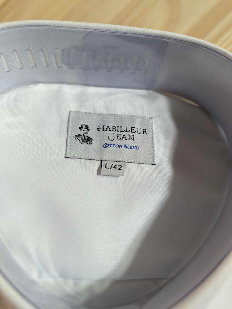 Puede incluir: Camisa blanca de cuello con una etiqueta que dice "Habilleur Jean Cotton Blend" y "L/42".